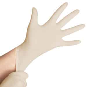 Une personne enfile un gant jetable Gant beige en latex non poudré, en le tirant sur sa main gauche avec sa main droite.