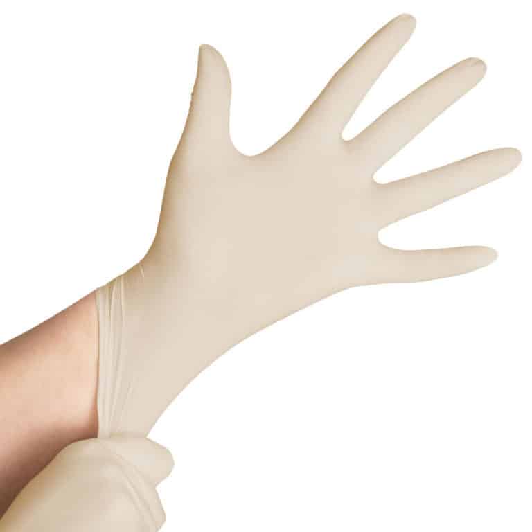 Une personne enfile un gant jetable Gant beige en latex non poudré, en le tirant sur sa main gauche avec sa main droite.