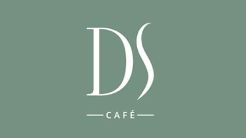 L'image montre un fond vert avec les initiales blanches "DS" au-dessus du mot "CAFÉ" en lettres majuscules, flanqué de deux lignes horizontales.