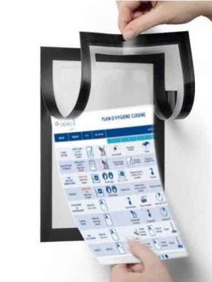 Une personne insère une feuille de plan d'hygiène dans un porte-document magnétique noir monté sur un mur blanc, mettant en valeur nos services de maintien de la propreté et de l'organisation.